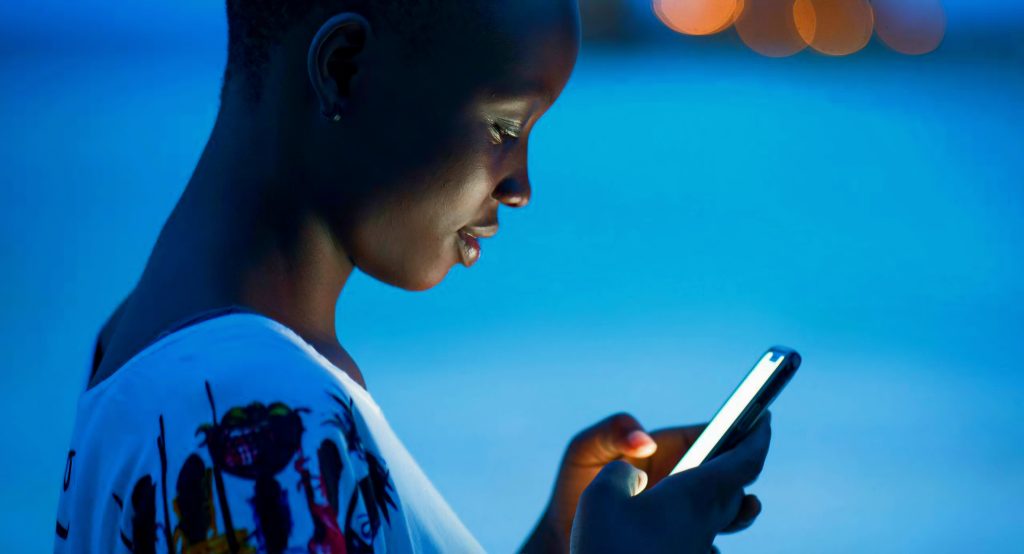 Tropical night beach for black girl using mobile phone