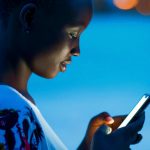 Tropical night beach for black girl using mobile phone